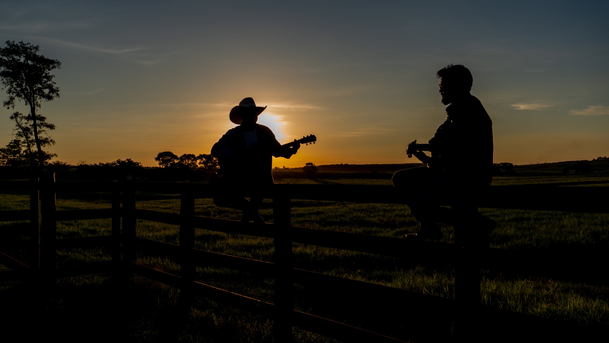 Rodrigo e Gustavo tocando violão ao pôr do sol